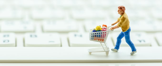 Figurine pushing a shopping cart over a keyboard.