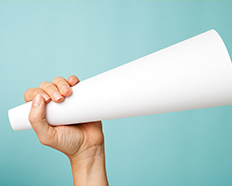 Hands holding a paper cone to speak louder